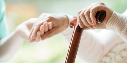 Disabled person with cane holding someone's hand