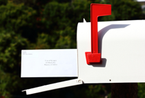 Mailbox with piece of mail sticking out and flag sticking up